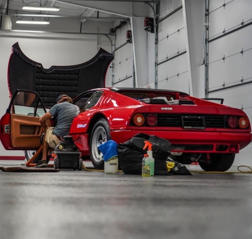 Detailer cleaning the interior of a classic red Ferrari in Kansas City